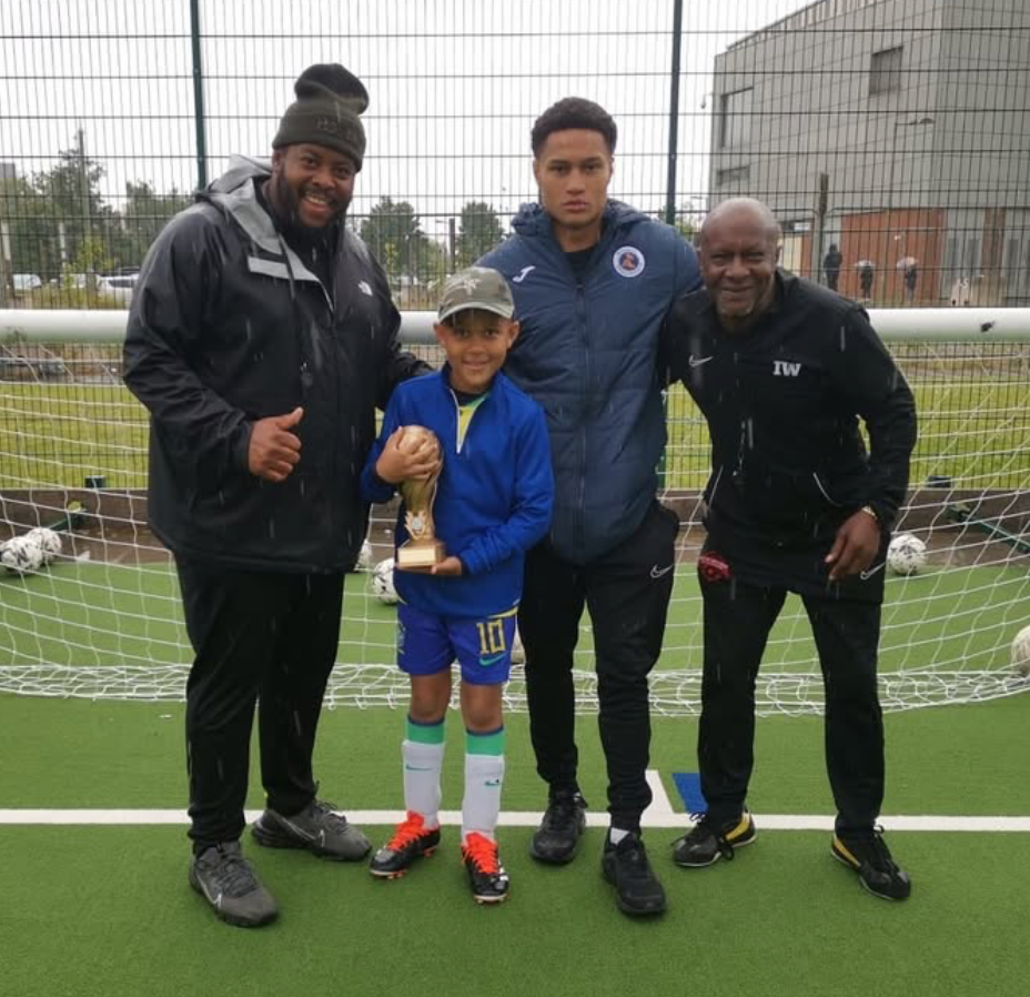 Coach Ian with successful young football player holding trophy at Soccer Inclusion Birmingham training facility