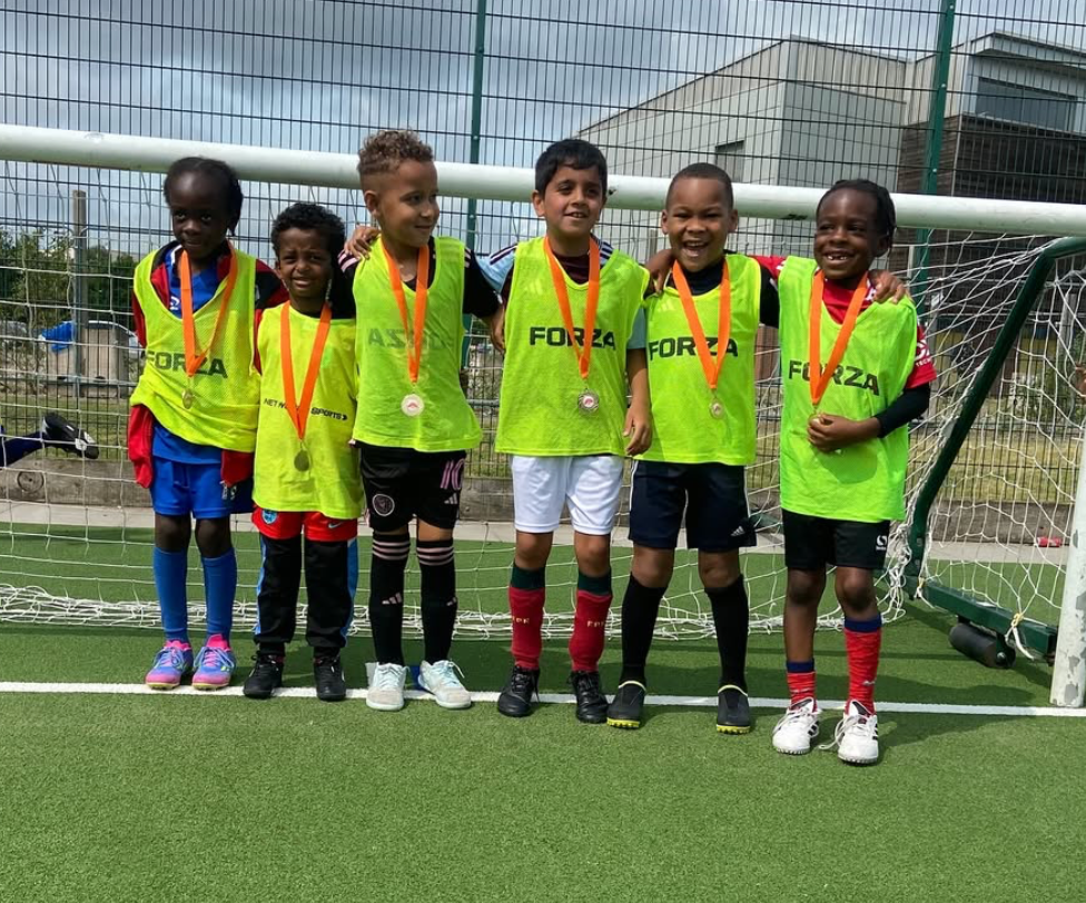 Young football players from Soccer Inclusion Birmingham proudly displaying their medals and trophies after successful training session